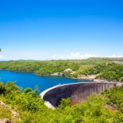 Qui pourrait croire en découvrant la richesse de sa faune et ses berges sauvages que le lac est artificiel ? En 1960, c’est la construction d’un barrage hydroélectrique, par le français André Coyne, qui crée le lac Kariba.
Lors de la saison des pluies, le niveau de l’eau monte et inonde les forêts alentours comme en témoigne le spectacle fascinant des troncs d’arbres qui émergent de la surface.
Ils forment alors des perchoirs de choix pour une grande variété d’oiseaux et donnent une atmosphère mystique au lieu. Une virée sur l’eau vous permettra de rencontrer quelques hippopotames et crocodiles ou encore de pêcher l’un des fameux poissons tigres.
Si vous passez par là en septembre, ne manquez pas le festival local dédié au dieu Nyaminyami.
La légende dit qu’il vivait là et que la construction du barrage l’a séparé de sa femme, ce qui a provoqué sa colère et déclenché une rupture tragique du barrage.